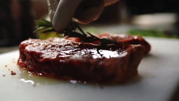 Vaření hovězího steaku doma, hovězí řízek na prkně, šťavnatý steak s grilovacími proužky, šéfkuchař dal rozmarýn na maso - Záběry, video