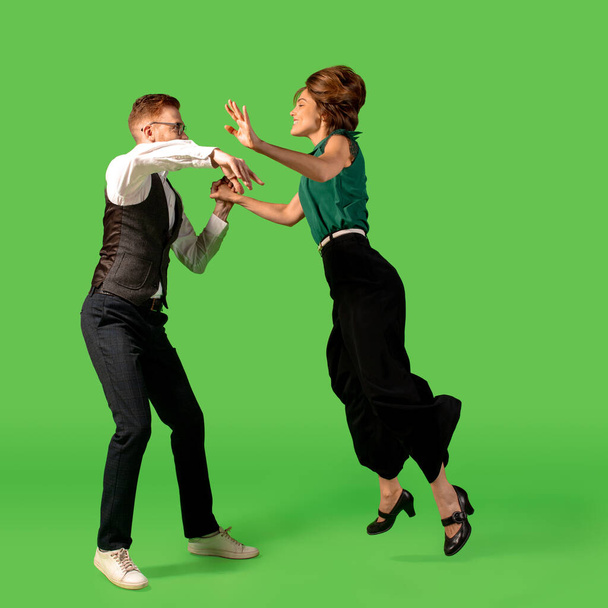 Old-school fashioned young woman dancing isolated on green background - Photo, Image
