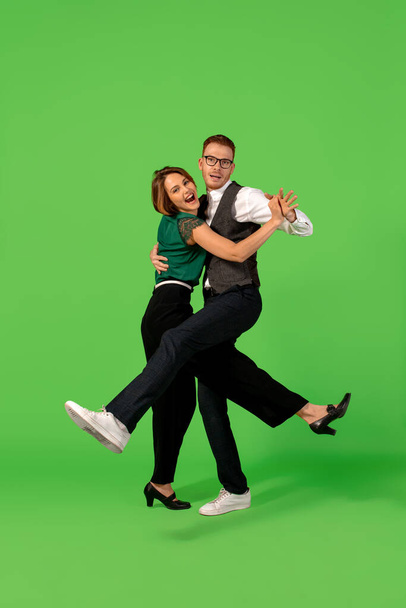 Old-school fashioned young woman dancing isolated on green background - 写真・画像