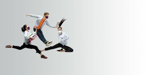 Happy office workers in face masks jumping and dancing in casual clothes or suit isolated on studio background. Creative collage. - Foto, Imagem