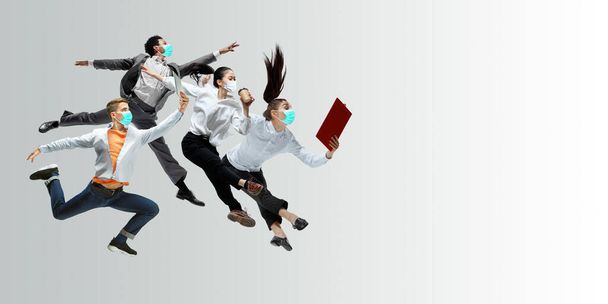 Happy office workers in face masks jumping and dancing in casual clothes or suit isolated on studio background. Creative collage. - Zdjęcie, obraz