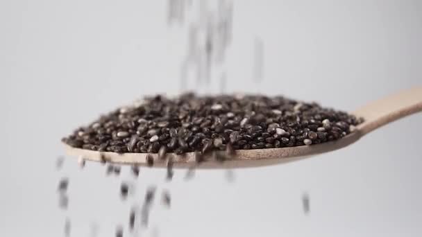Pouring chia seeds into a dessert wooden spoon close-up. Macro. Slow motion - Materiał filmowy, wideo