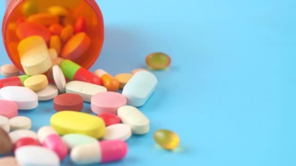 Close-up van vele kleurrijke pillen en capsules op blauwe achtergrond  - Video