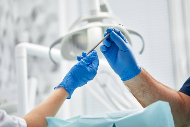 Primer plano de las manos de un dentista y enfermero cirujano sobre un quirófano durante una operación de implante dental - Foto, imagen
