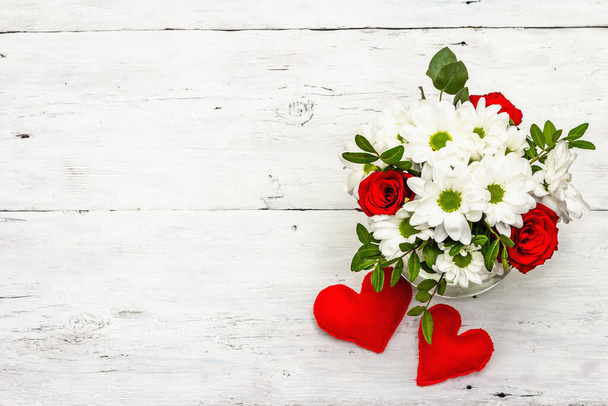 A bouquet of fresh flowers and red felt hearts. Valentine's day or Wedding concept. White old planks background - Photo, Image