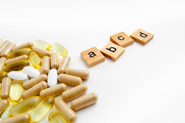 inscription A B C E en cubes de bois sur fond blanc de différentes pilules - Photo, image