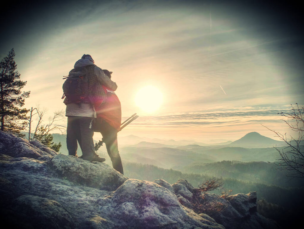 Silhouetten von zwei fotografierenden Reisenden im Sonnenuntergang über den Bergen. Abstrakter Filter. - Foto, Bild