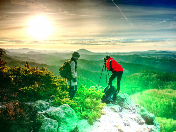 トラベルライフスタイルと写真のコンセプトリアビュー。写真家の旅行者はハイキングを楽しみ、写真家は高い山を背景に女性の写真を撮る。アブストラクトフィルター. - 写真・画像