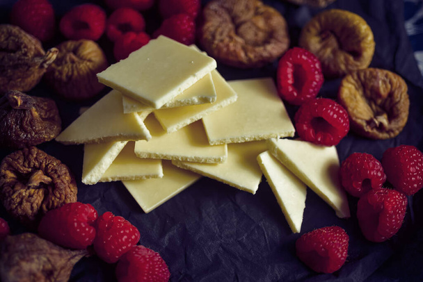 pieces of white chocolate amid fresh raw red raspberries and dried figs - Photo, Image