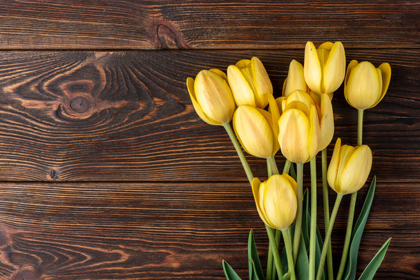 Tulipani gialli su sfondo di legno scuro. - Foto, immagini