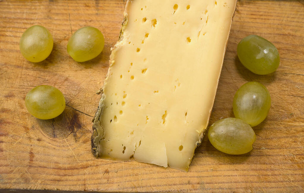 Franse kaas en druiven op een houten plank - Foto, afbeelding