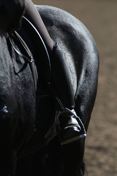 Alter Ledersattel mit Steigbügeln für Springrennsattel auf dem Rücken eines Sportpferdes. Hintergrund Pferdesport-Veranstaltung - Foto, Bild