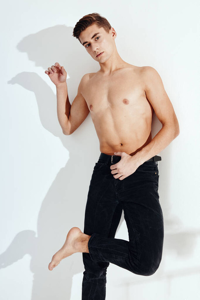 Хлопець стоїть на одній нозі в чорних штанях і голий торс
 - Фото, зображення