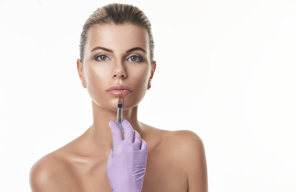 beautiful young woman with purple gloves holds a syringe - Photo, image