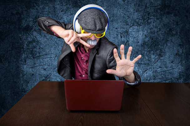 Senior tanzt vor seinem Laptop mit blauem Hintergrund. horizontal - Foto, Bild