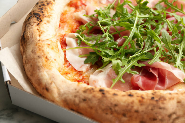 Tasty pizza with meat and arugula in cardboard box, closeup - Foto, imagen