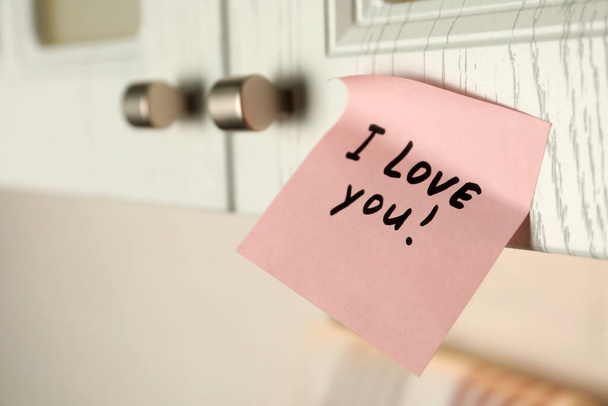 Sticky paper with words I Love You on door of kitchen cabinet indoors, closeup - 写真・画像