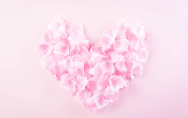 Concepto de amor y San Valentín. Corazones rosados hechos de pétalos de rosa sobre fondo pastel. Vista superior plana. - Foto, imagen