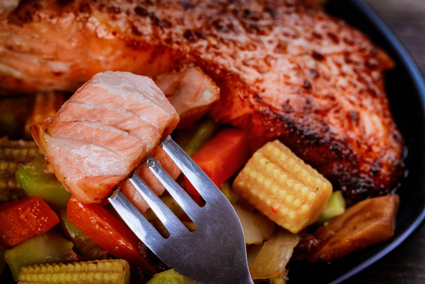 Grilled juicy salmon fillet with steamed vegetables on black plate. Close up. - Photo, Image