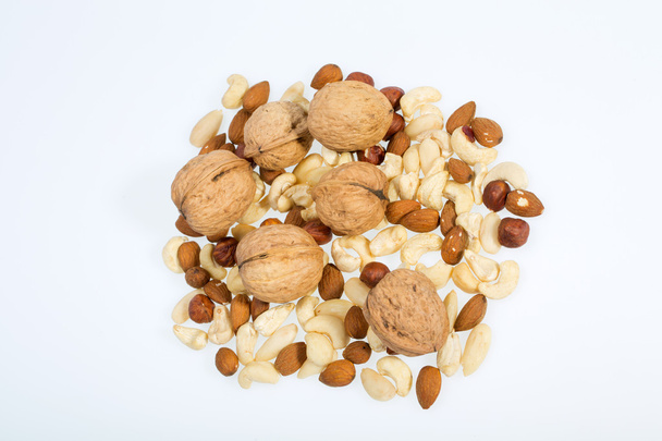 Smíšený ořechy - lískové oříšky, vlašské ořechy, Kešu ořechy, piniové oříšky izolovaných na bílém pozadí - Fotografie, Obrázek
