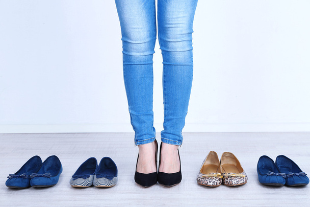 Girl chooses shoes in room on grey background - Foto, imagen