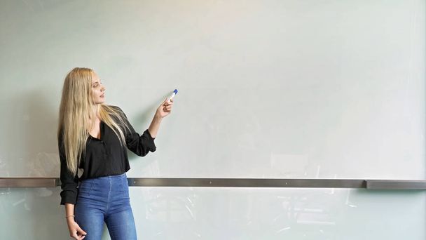 Zakelijke blonde vrouw. Een docent die online een les of lezing geeft over blanco whiteboard in onderwijs of bedrijfsconcept. maak een model. - Foto, afbeelding