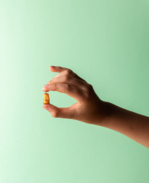 Hand of Caucasian teenager boy with haw stump in fingers. Small fruit leftovers in human hand. Copy space. Unrecognizable person. Vertical orientation. Healthy eating concept. Green mint background. - Φωτογραφία, εικόνα
