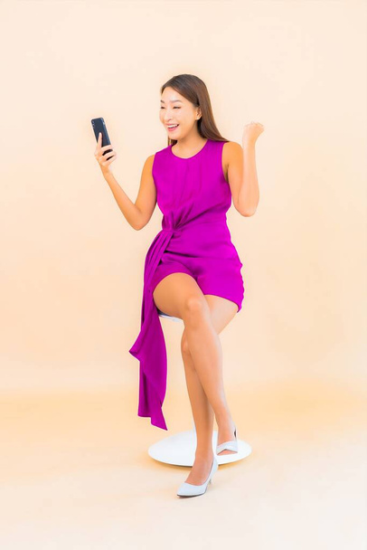 Ritratto bella giovane donna asiatica utilizzare smart cellulare su sfondo colore - Foto, immagini