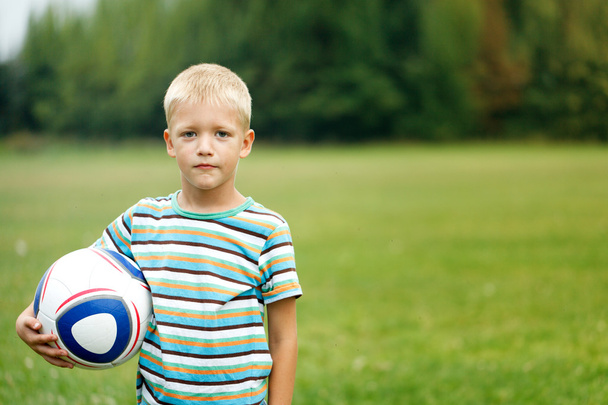Boy standing and holding ball under his arm - Фото, зображення
