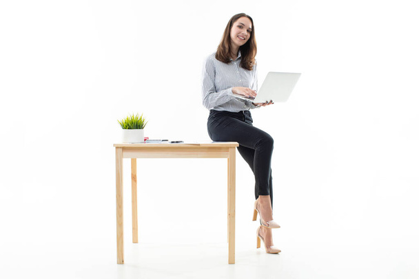 Mujer joven sentada en una mesa y escribiendo en una computadora  - Foto, imagen