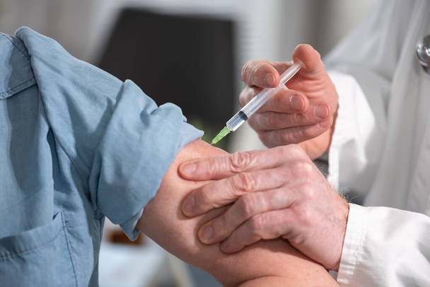 女性患者にワクチンを注射する医師 - 写真・画像