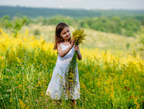 Cute little girl holding wildflower bouquet - Fotoğraf, Görsel