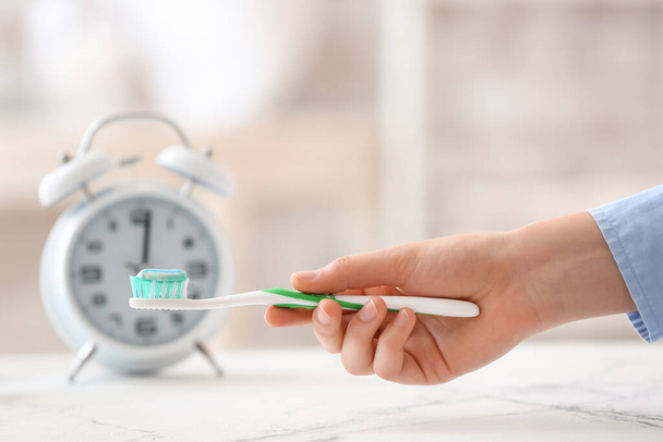 Mano femenina con cepillo de dientes y pasta en casa - Foto, Imagen