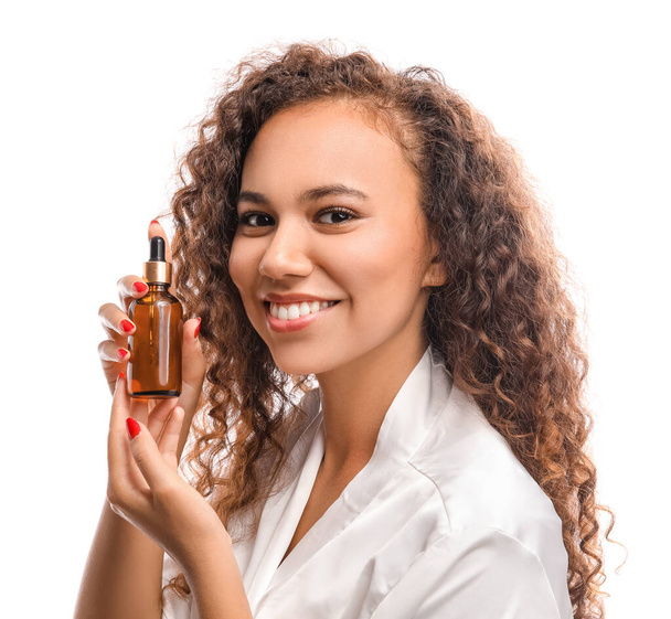 mooie jonge vrouw met cosmetische olie op witte achtergrond - Foto, afbeelding