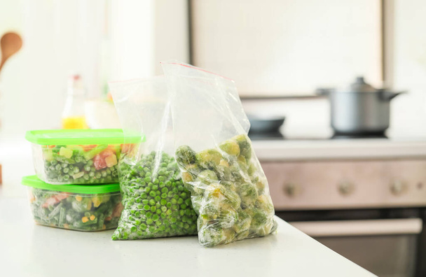 Plastové nádoby a tašky se zmrazenou zeleninou na stole - Fotografie, Obrázek