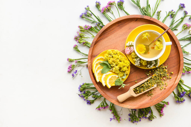 Cup with floral tea, flowers and lemon on light background - Photo, Image