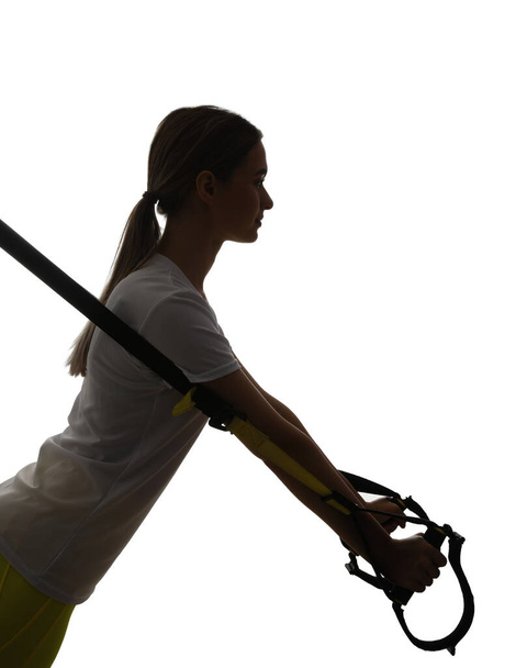 Silhouette of sporty young woman training with TRX straps on white background - Fotografie, Obrázek