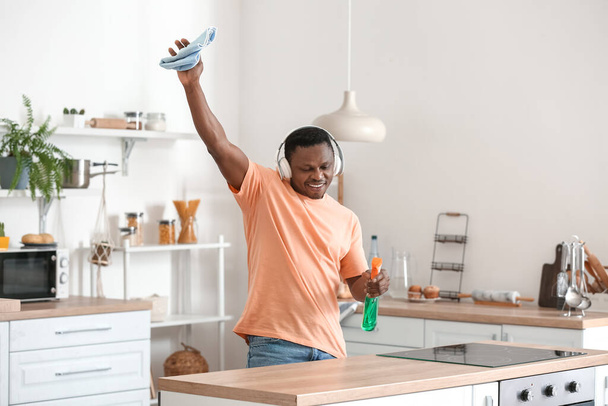 Afroameričan poslouchající hudbu při čištění kuchyně - Fotografie, Obrázek