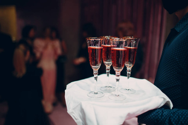 Glasses of rose sparkle wine on waiter hand dish - Photo, Image