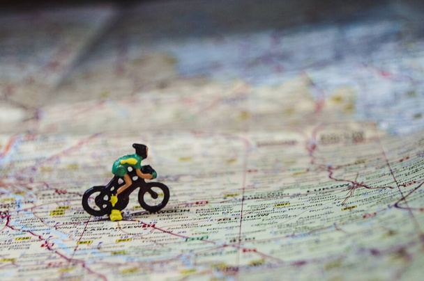 φιγούρες των ποδηλατών ιππασίας στο χάρτη ποδηλατικό ταξίδι ποδηλασία έννοια αγώνα μακροφωτογραφία γκρο πλαν λεπτομέρειες σχέδιο του ταξιδιού ποδηλασία τουρισμό αθλητισμού αναψυχή - Φωτογραφία, εικόνα