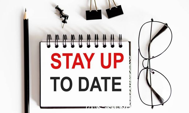 STAY UP TO DATE memo geschreven op notebook met pen en bril - Foto, afbeelding