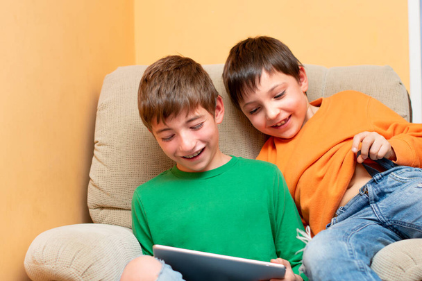 двоє дітей сміються зі столом в руці на дивані
 - Фото, зображення
