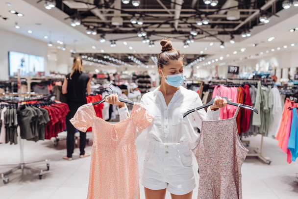 Giovane donna shopping abbigliamento boutique di abbigliamento con maschera protettiva - Foto, immagini