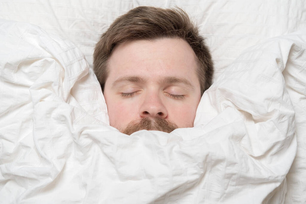 Cute, charming man asleep wrapped in a blanket.  - Foto, Imagen
