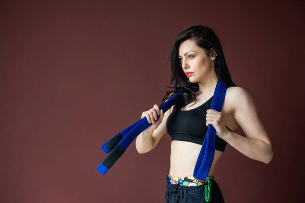 Portrait beautiful athletic woman with blue belt. Martial arts concept. Indoor, studio shot, background with copy space advertising. - Photo, Image