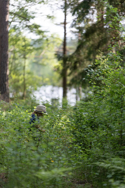 fiú ül az úton az erdőben egy fedora kalap - Fotó, kép