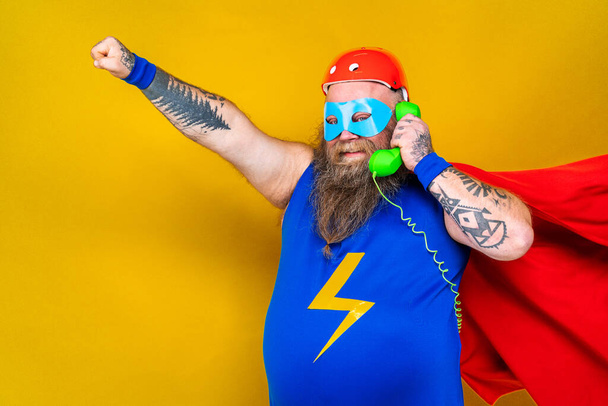 Funny fat man with superhero costume acting as superhuman with special powers, portrait on colored background - Foto, immagini