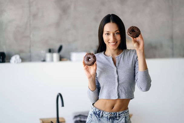 Retrato de mulher alegre segurando saboroso donut em casa - Foto, Imagem