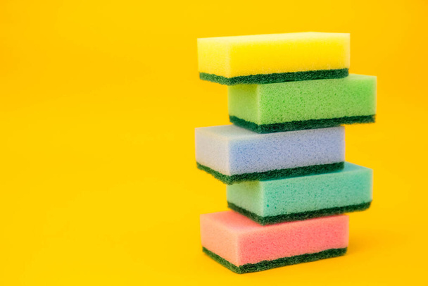 Multicolored sponges for cleaning folded pyramid on a yellow background. Space for text. - Zdjęcie, obraz
