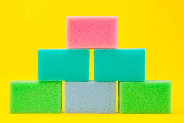 Multi-colored foam rubber sponge for cleaning and washing dishes on a yellow background. Top view, pattern. - Фото, зображення
